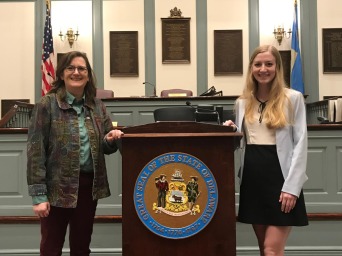 Blond girl to the right of presentation pedestal with other woman to the left 