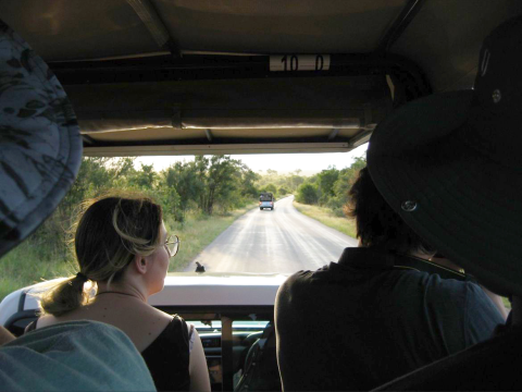 Looking out the front window of a jeep on a game drive, with a young woman sitting in the front seat.