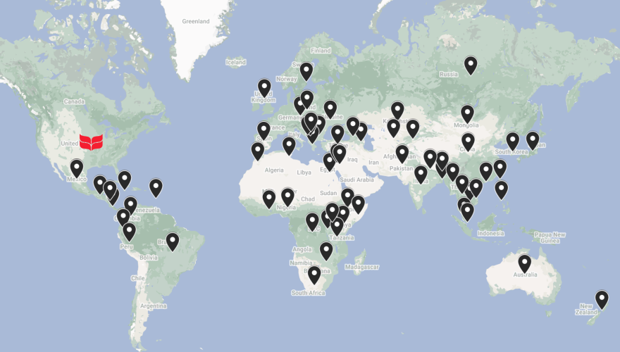 World map with black pinpoints representing Grinnellians’ passport countries and a red laurel leaf logo pinpointing Grinnell, Iowa